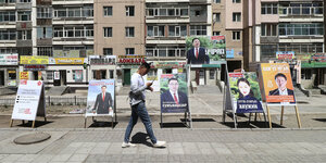 Ein junger Mann geht an Wahlplakaten vorbei