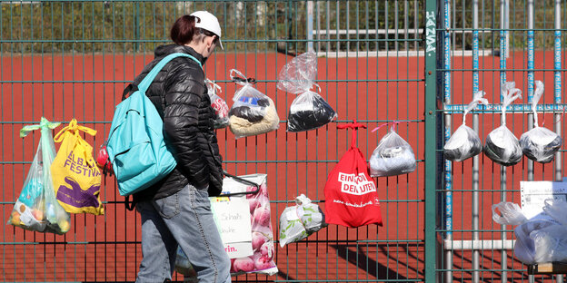 Frau mit Rücksack steht vor einem Spendenzaun