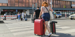 Reisende gehen mit Koffern zum Terminal des Flughafens Berlin Schönefeld