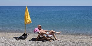 Ein Mann in der Sonnen liege am Strand