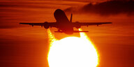 Ein Flugzeug startet vor der untergehenden Sonne