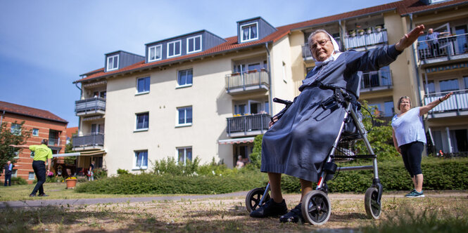 Eine ältere Frau mit Rollator macht Gymnastik