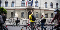 Demonstrierende RadfahrerInnen vor einem Gebäude mit Fahnen