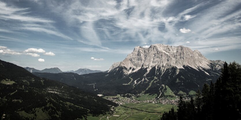 Ein weites grünes Tal vor einem hoch aufragenden Berg