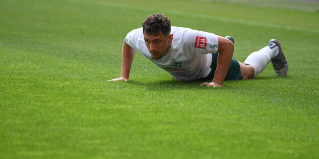 Ein Bremer Fußballer liegt auf dem Rasen