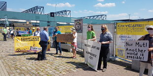 Aktivist:innen protestieren vor der Messehalle, in der die Kommission tagt