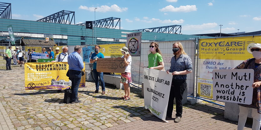 Aktivist:innen protestieren vor der Messehalle, in der die Kommission tagt