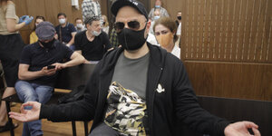 Mann mit Gesichtmaske sitzt in Gerichtssaal