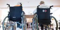Zwei SeniorInnen sitzen nebeneinander im Rollstuhl in einem Pflegeheim