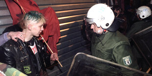 Ein Punk mit Fahne, ein Polizist mit Helm