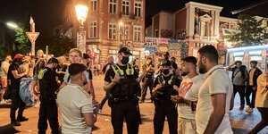 Polizisten gestikulieren im Gespräch mit jungen Männern.