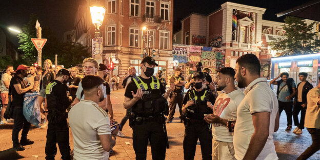 Polizisten gestikulieren im Gespräch mit jungen Männern.