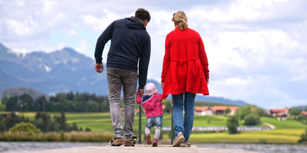 Eine Familie mit Kleinkind an einem Steg am See