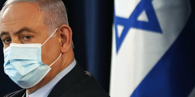 Benjamin Netanjahu mit Gesichtsmaske vor einer Israel-Fahne