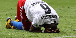 Fußballspieler David Kinsombi von HSV kniet gesenkten Kopfes auf dem Rasen