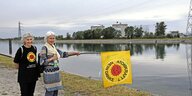 Zwei Demonstrantinnen mit einer Anti-Atom-Fahne am Rhein vor dem AKW Fessenheim