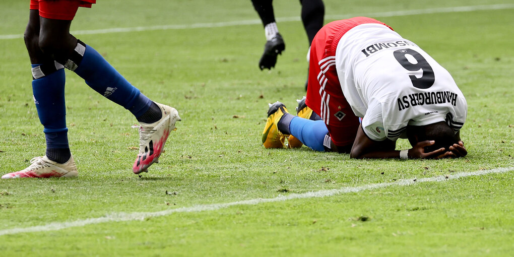 Ein Fussballspieler kniet auf dem Rasen nieder.