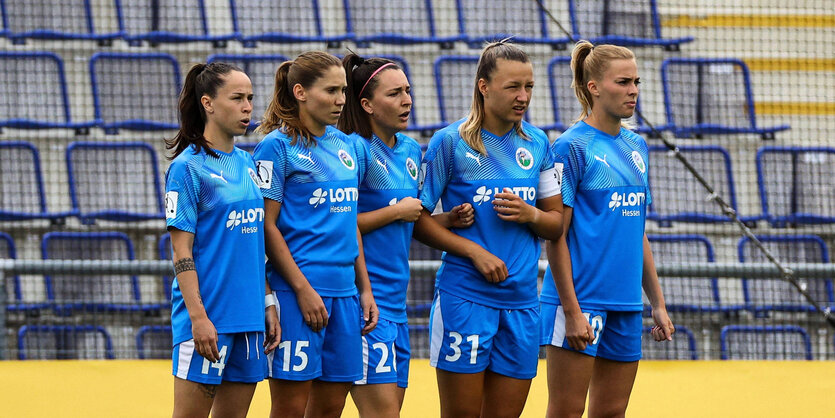 Fussballerinnen stehen in einer Reihe in einem Stadion.