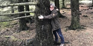 Ein Mann umarmt einen Baum