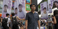 Joshua Wong steht vor Wahlplakaten