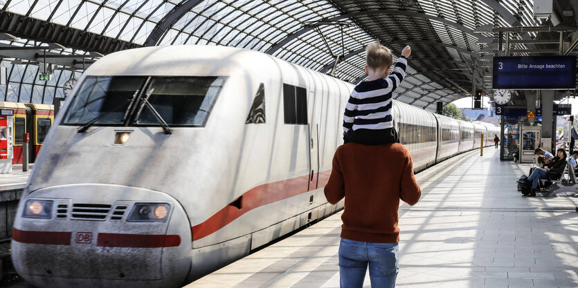 auf einem Bahnsteig steht ein ICE, davor ein Mann, der ein Kind auf den Schultern trägt