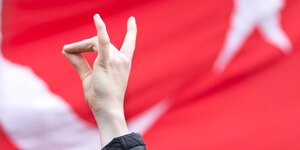 Die Finger einer Hand formen ein Zeichen vor türkischer Fahne