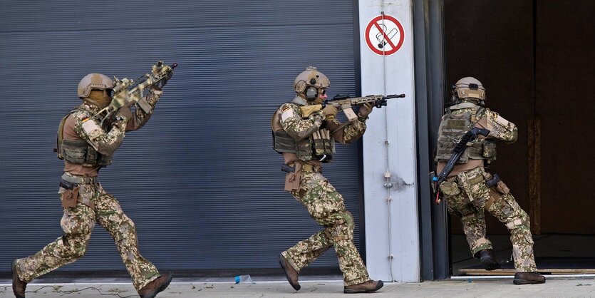 Kommando Spezialkräfte rennen an einer Mauer entlang.