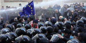 Demonstration mit EU-Fahne vor Polizisten mit Helmen.