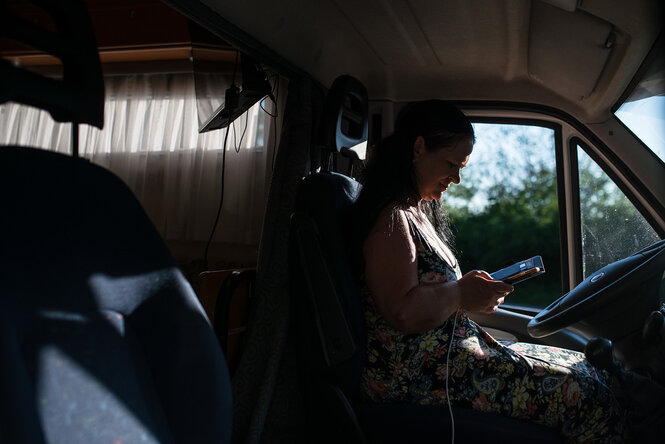 Eine Frau sitz am Steuer eines Wohnmobils und schaut auf ihr Handy