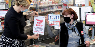 Familienministerin Franziska Giffey hängt in einem Supermarkt ein Plakat auf, dass Frauen auf Hilfsprogramme für Opfer häuslicher Gewalt aufmerksam machen soll