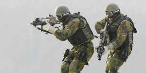 Zwei KSK-Soldaten in schwerer Uniform, mit Helmen und Gewehren im Anschlag