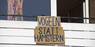 Auf einem Pappschild an einem Balkon steht: "Vögeln statt Hamstern"