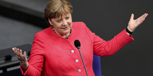 Bundeskanzlerin Merkel breitet am Redepult im Bundestag die Arme aus.