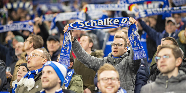Schalker Fans, die ihre Schals hochstrecken