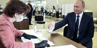 Präsident Putin zeigt in einem Wahllokal seinen Pass.