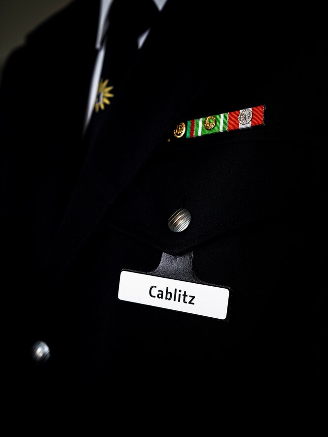 Ein Detailblick auf Cablitz' Uniform samt Namensschild