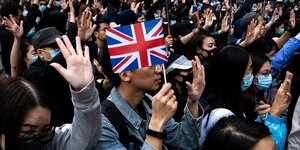 Ein Mann steht in einer Menschenmenge und hält ein britisches Fähnchen in der Hand