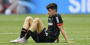 Frustrierter Fußballer sitzt auf dem Rasen
