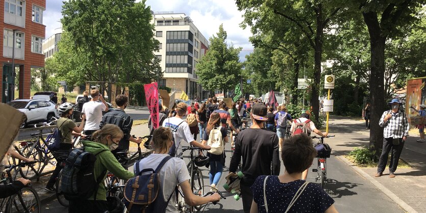 Demonstrierende laufen auf der Straße. Einige schieben Fahrräder neben sich her.