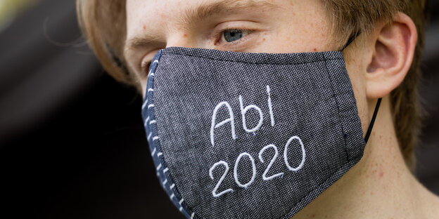 Abiturient mit Gesichtsmaske, auf die "Abi 2020" gestickt wurde