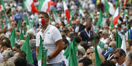 Demonstrierende auf einem Platz in Rom. Sie tragen teilweise Mund-Nasen-Schutz in den Farben Italiens und schwenken italienische Flaggen.