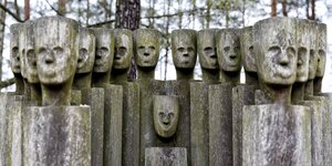 Gespenstisch aussehende Holzskultpuren stehen vor einem Waldstück: Sie sollen an Opfer des Konzentrationslager Sachsenhauser erinnern