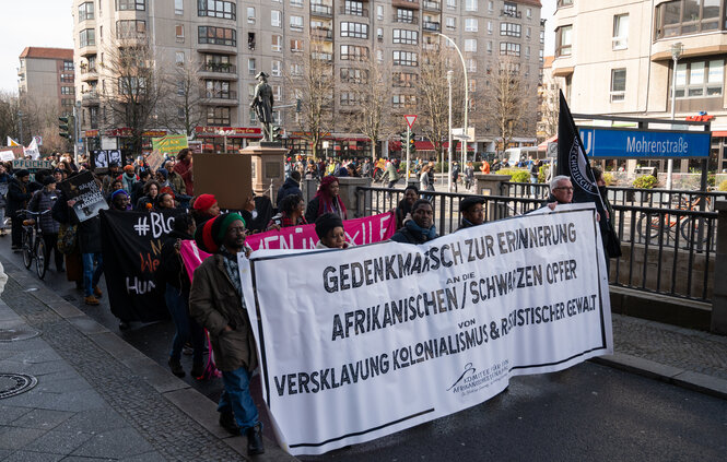 Viele Menschen protestieren vor einem U-Bahnhof zur Erinnerung an die Verbrechen des Kolonialismus