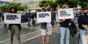Demonstrierende stehen auf der Straße. Auf ihren Schildern stehen Botschaften gegen Nazis und Rechte bei Polizei und Bundeswehr.