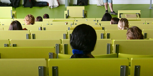 Einige Studiernde sitzen in einem halb gefüllten Hörsaal