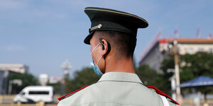 Ein chinesischer Polizist trägt einen Kopfhörer im Ohr