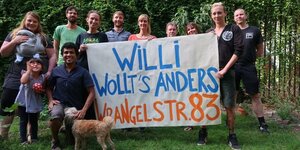 Die Hausgemeinschaft hält ein Plakat "Willi wollt's anders"