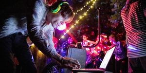 DJ am Laptop legt auf bei einer Party in der Berliner Hasenheide