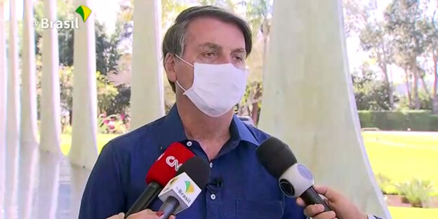 Jair Bolsonaro mit Gesichtsmaske vor Reportermikrofonen