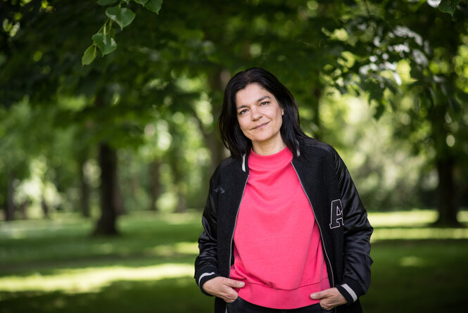 Schauspielerin und Sängerin Jasmin Tabatabai steht im Schlosspark in Pankow und schaut freundlich in die Kamera